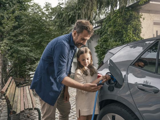 Klimabewusst leben - Vater und Tochter am E-Auto