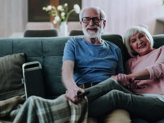 Paar auf dem Sofa mit dem OSKAR TV-Verstärker neben sich